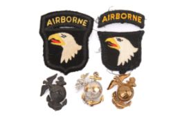 Three US Marine Corp cap badges and two Airborne cloth badges.