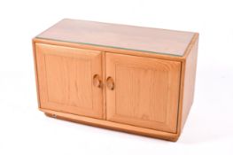 Ercol Windsor TV entertainment cabinet stand. Having two doors opening to reveal a glass shelf.