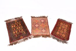 Three small Afghan style wool rugs on a red ground.