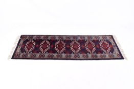 An Afghan Baluch style wool runner rug on a dark blue ground.