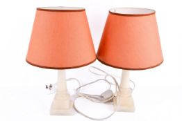 A pair of alabaster table lamps, carved columns on square bases.