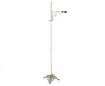 A white painted wrought iron standard lamp with scrolling supports,