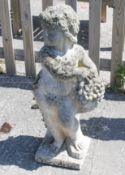 A reconstituted stone garden statue of a cherub holding a bunch of grapes.