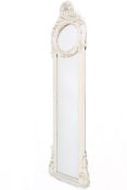 A contemporary tall slim wall mirror with ribbon and floral decorated white frame.