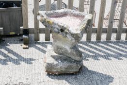 A garden stone bird bath in three organic form sections.