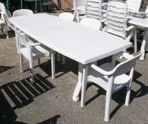 A white plastic garden patio table and set of five Allibert Madrigal stacking chairs.