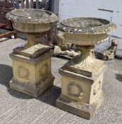 Pair of composition stone garden urns on plinths, one with recently repaired central column.