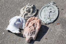 A group of four garden wall ornaments.