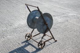 A metal garden reel on frame with wheels. Reel and wheels rotate.