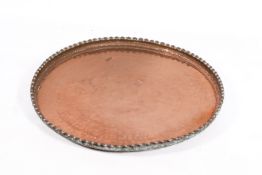 A large circular middle eastern copper platter with decorative crimped edge.