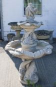Large reconstituted stone garden water feature two tier fountain. Having putti and fish decoration.