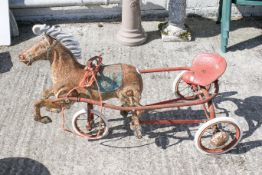 A vintage red tricycle in the form of a horse. Wheels turn and steer.