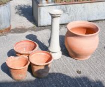 A group of terracotta garden pots along a reconstituted stone pedestal stand.