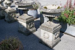 Pair of composition stone garden urns on plinths.