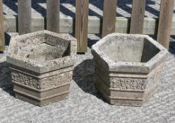 A pair of reconstituted stone planters of hexagonal form with decorative floral moulding to the