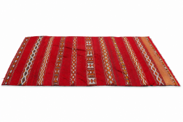 A Moroccan style Kilim rug on a red ground (af). Having geometric and patterned stripes.