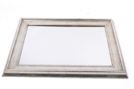 A contemporary wall mirror with mottled silver frame.