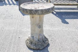 A composite stone garden bird bath. Having tree trunk effect base.