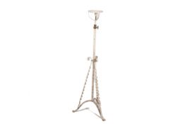 A white painted wrought iron standard lamp with scrolling supports,