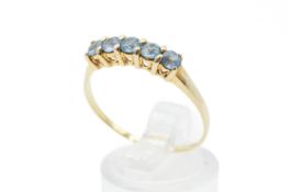 A yellow metal gold dress ring set with five round faceted topaz, each of 3.2mm diameter.