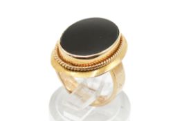 A yellow metal dress ring set with one flat oval section of onyx. Onyx circa 1.5cm x 1.