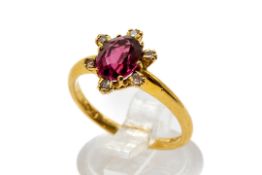 An 18ct gold and garnet dress ring. The oval cut garnet of circa 1.
