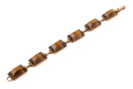 A yellow metal mounted 'tiger's eye' panel bracelet. The six domed panels circa 1.1cm x 1.9cm x 0.
