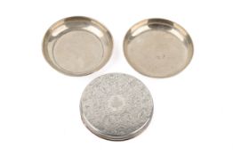 Two small round silver dishes and a silver lid.