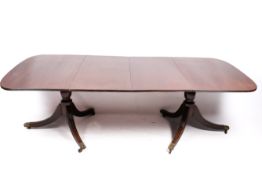 An extending 20th century mahogany Regency style dining table with two leaves.