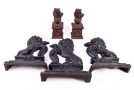 Three black lacquered cast iron 'lion' door stops and a pair of rust effect frogs on pedestals.