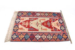 A Turkish Kilim flatweave rug or wall hanging on a dark blue ground.
