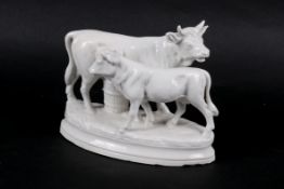 A white glazed porcelain figurine group modelled as a cow and her calf.