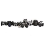 A collection of eight assorted vintage film cameras plus three spare lenses.