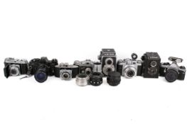A collection of eight assorted vintage film cameras plus three spare lenses.