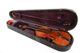 A vintage two piece back violin with two bows in a coffin shaped case.