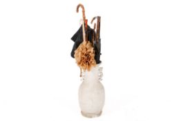 A pottery umbrella stand and a collection of umbrellas.