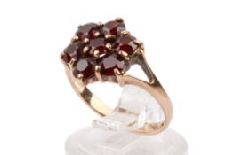 A 9ct gold and garnet cluster ring. The flower head measuring circa 1.2cm x 1.