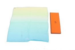A Hermes graduated green and blue silk scarf. 45cm x 45cm, in the original box.
