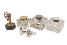 Three silver mounted glass inkwells and a novelty brass cigar cutter.