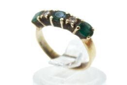 A yellow metal dress and emerald ring. Set with three oval faceted emeralds of 0.