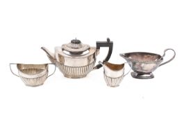 A matched late Victorian three-piece silver tea set together with a silverplated sauce boat.