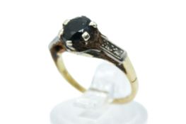 An 18ct gold ring set with one dark blue sapphire of 6mm diameter and three single cut diamonds to