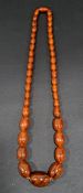 GRADUATED AMBER COLOURED BEAD NECKLACE the largest bead approximately 28.5mm long and the smallest