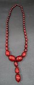 GRADUATED CHERRY AMBER BEAD NECKLACE with a further three bead drop, the largest bead measuring