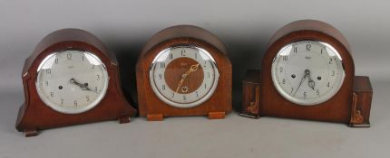 Three Smiths Enfield dome top mantle clocks all featuring Arabic numeral markers. One missing