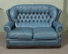 A blue leather button back two seater sofa.