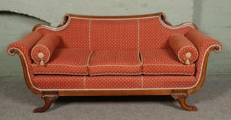 A regency style mahogany scroll arm sofa, with swan neck top rail and raised on squat carved