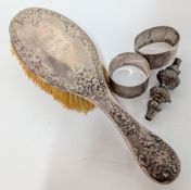 A silver hairbrush, with elaborate embossed floral decoration, together with two silver napkin