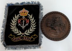 A wooden Tampion of HMS Exeter, depicting a crowned lion, together with a Royal Navy embroidery with