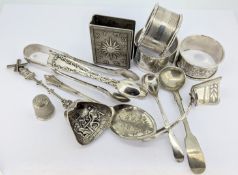 A collection of silver pieces, to include matchbox case decorated with astrology symbols, napkin